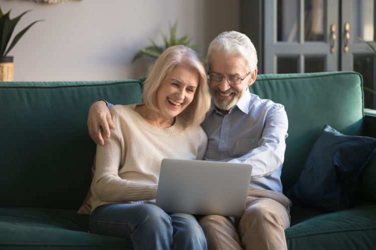 Happy elderly couple looking at homes on the computer