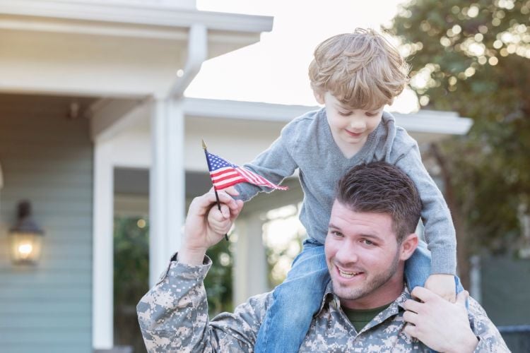 Active duty military and his son outside the home he purchased with a VA Loan